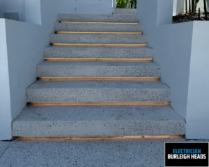 Outdoor concrete staircase with tiled steps leading upward beside a white wall.